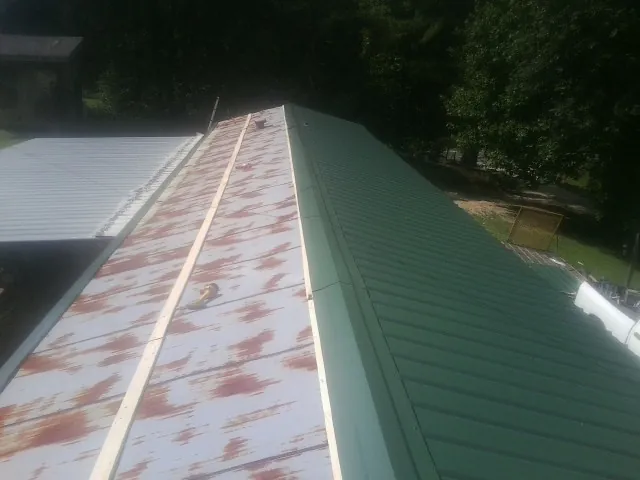 Old rusted panels beside newly installed green metal roofing — Wind Damage Roof Repair by Roofing Brothers in Scottsmoor