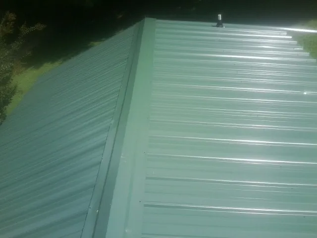 New green metal panels meeting at the ridge of a roof — Flat Roof Repair work by our crew in Scottsmoor