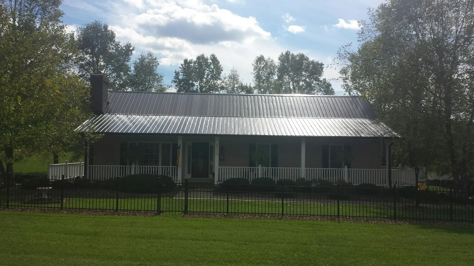 Gray metal roof on a brick ranch with a full width front porch — Gutter Guard Installation work by our crew in Scottsmoor
