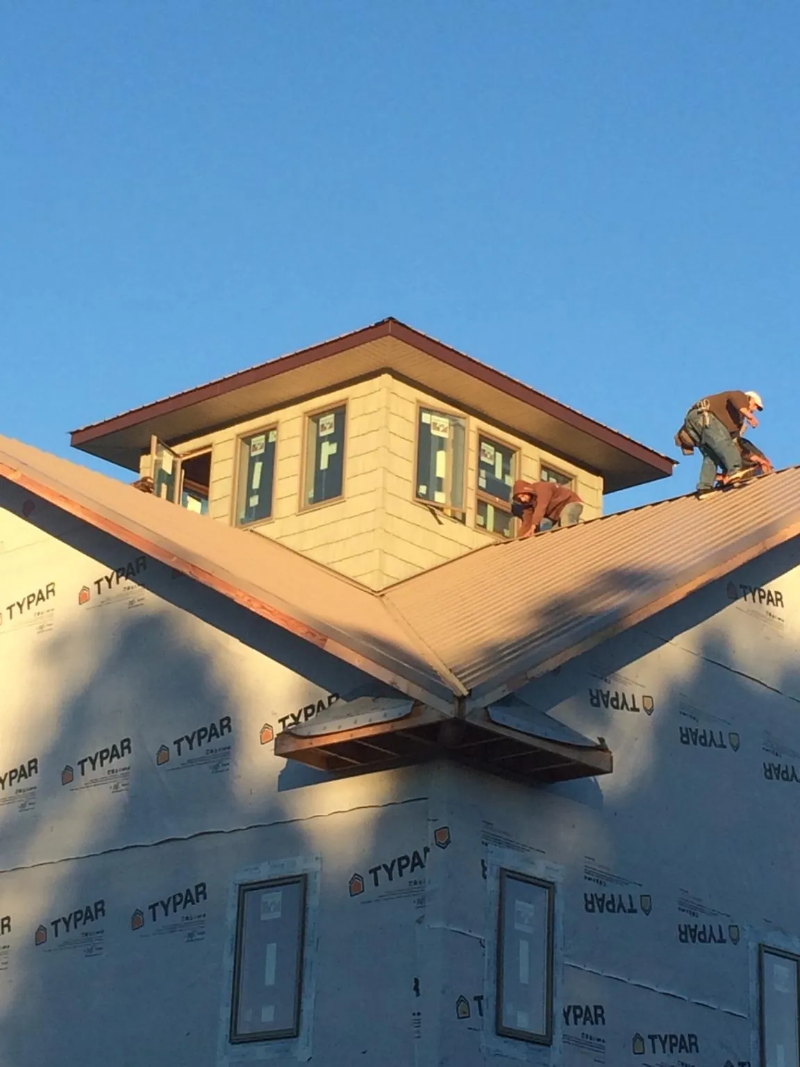 Roofers working around a rooftop cupola on a new metal roof at sunset — Roof Waterproofing in Scottsmoor by Roofing Brothers